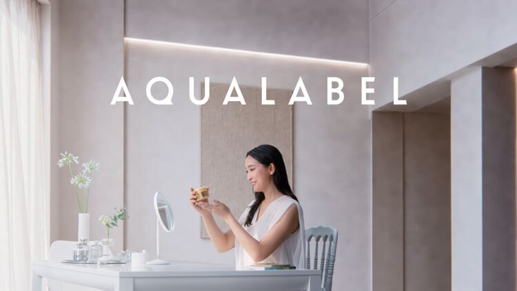 鏡の前で商品を手にする杏さんと、AQUALABELのロゴ