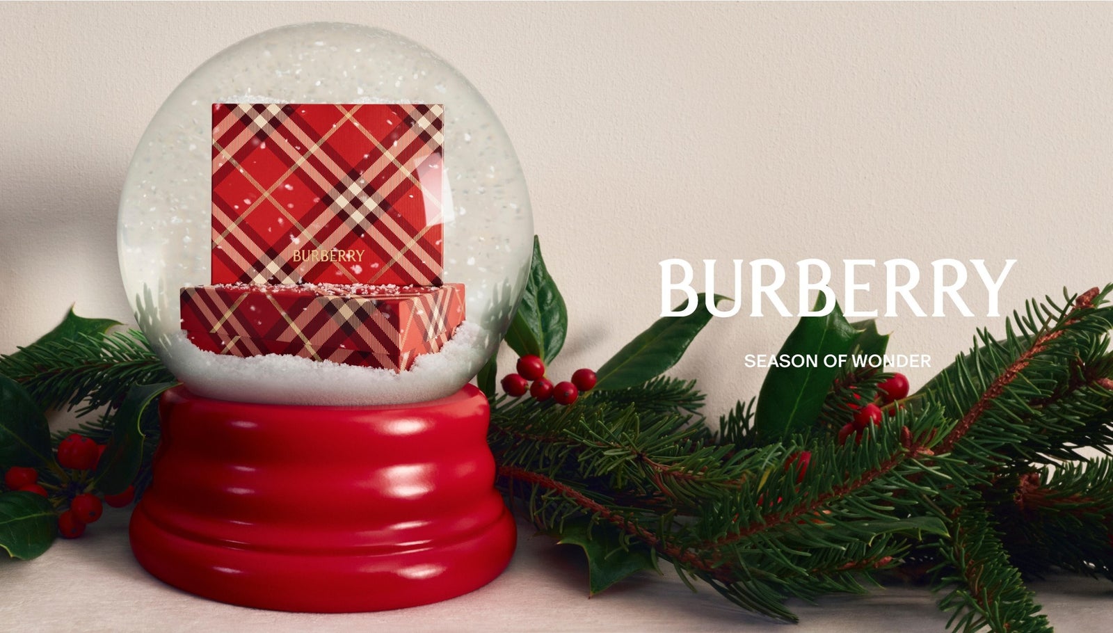 赤いバーバリーチェックのギフトボックスが入ったスノードームと、モミの枝と赤い実。右にBURBERRYのロゴ
