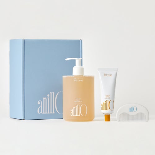 A hand & body wash, hand cream and hair comb lined up in front of a blue box