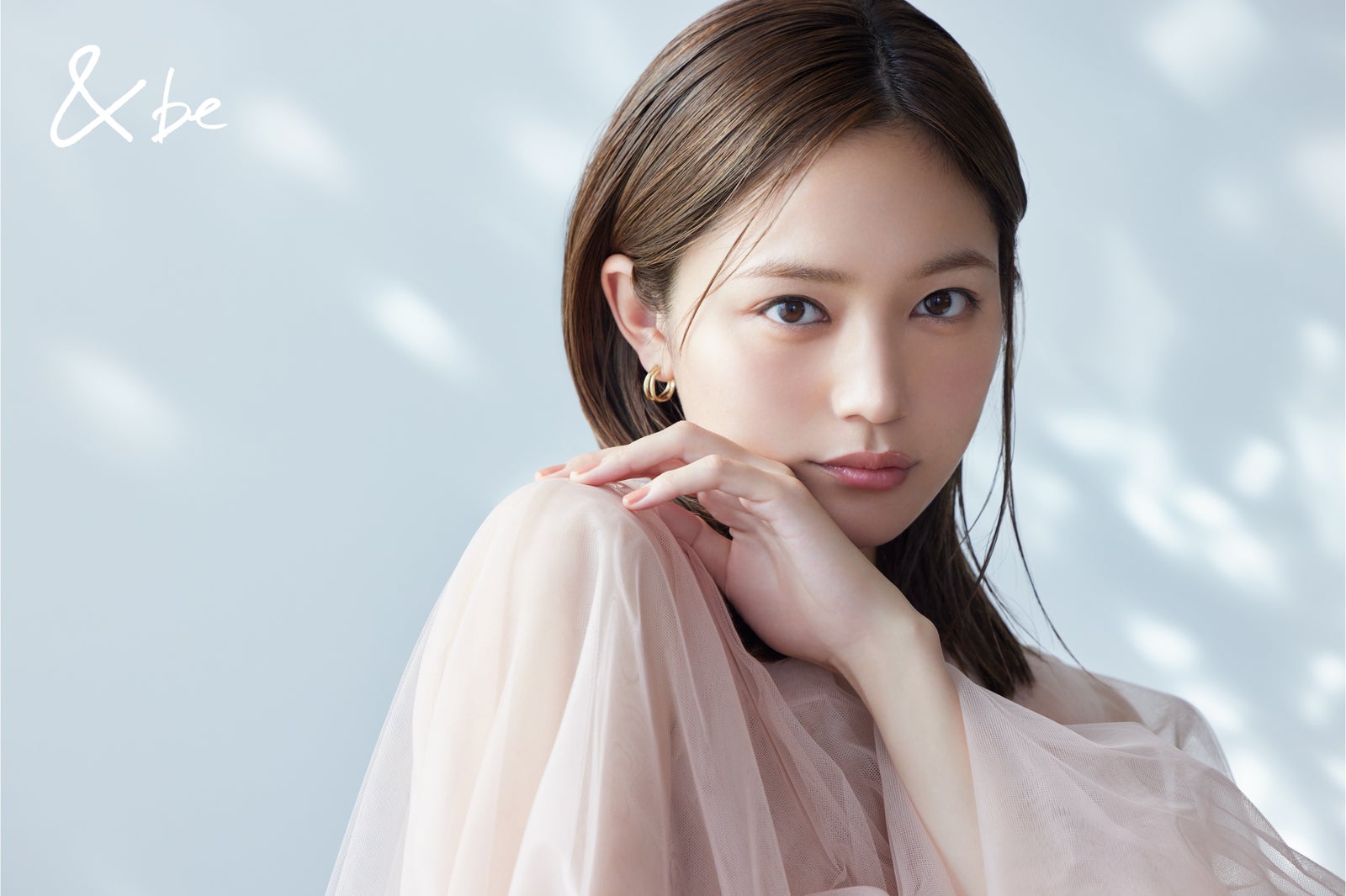 ピンクのシアー素材の服を着て頬杖をつく川口春奈さんの＆beのビジュアル