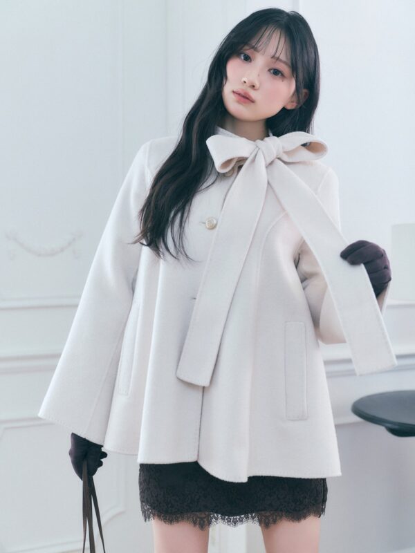 大きなリボンを添えた白いコートとショートパンツの着用例
