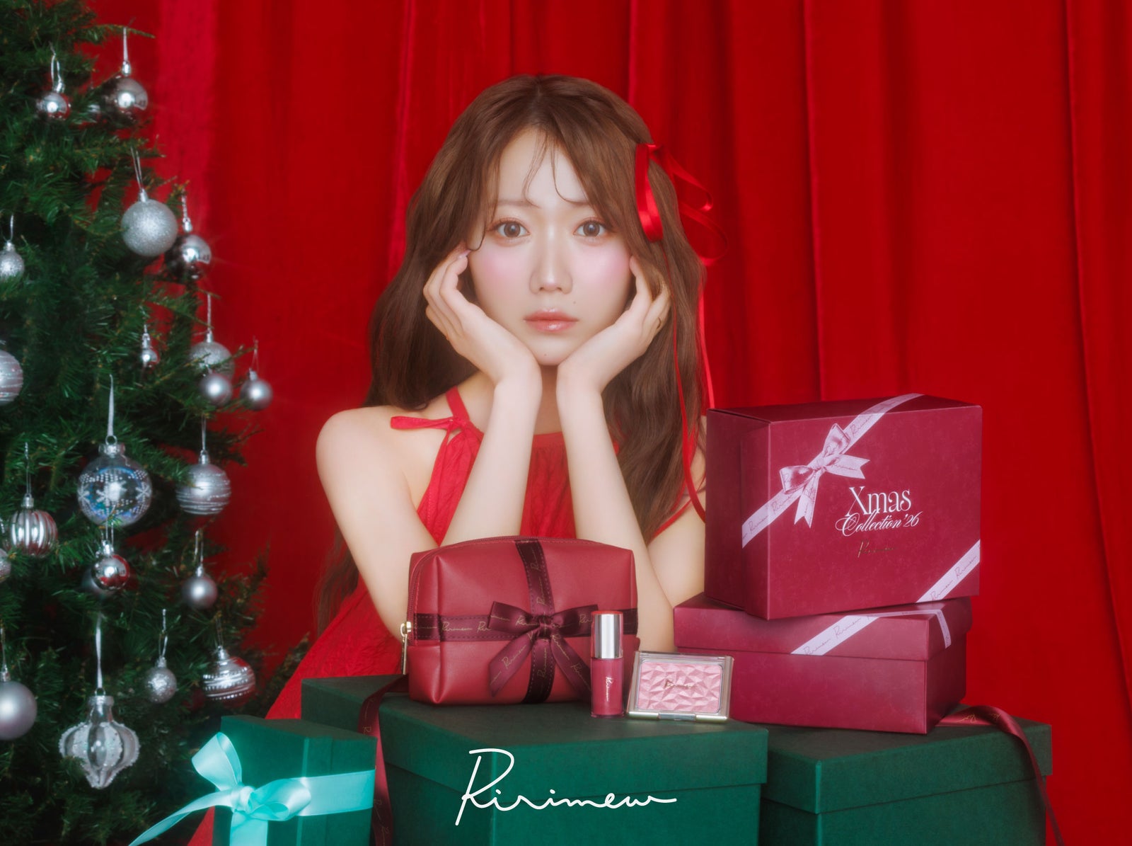 赤いカーテンとクリスマスツリーを背に、コフレのBOXに囲まれて座る大谷映美里さん