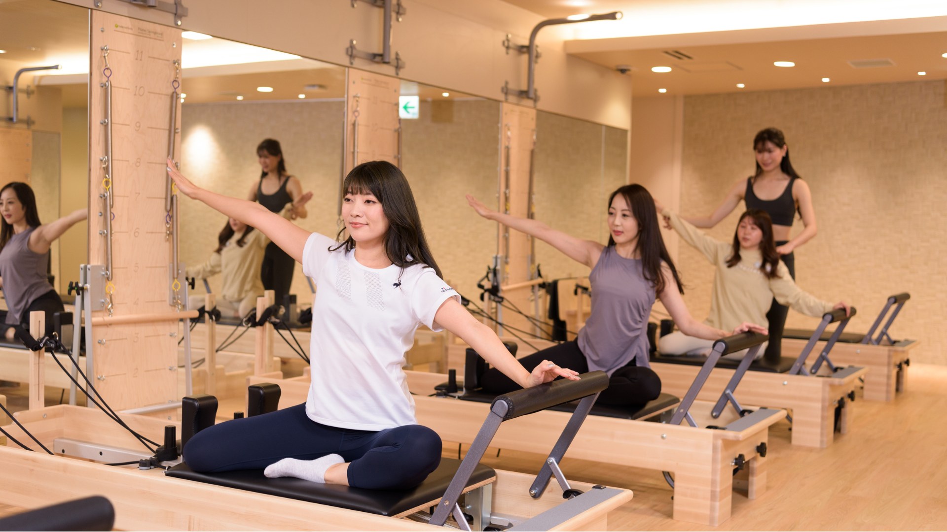 Repilatesのマシンに座り、腕を伸ばして動く女性たち(イメージ)