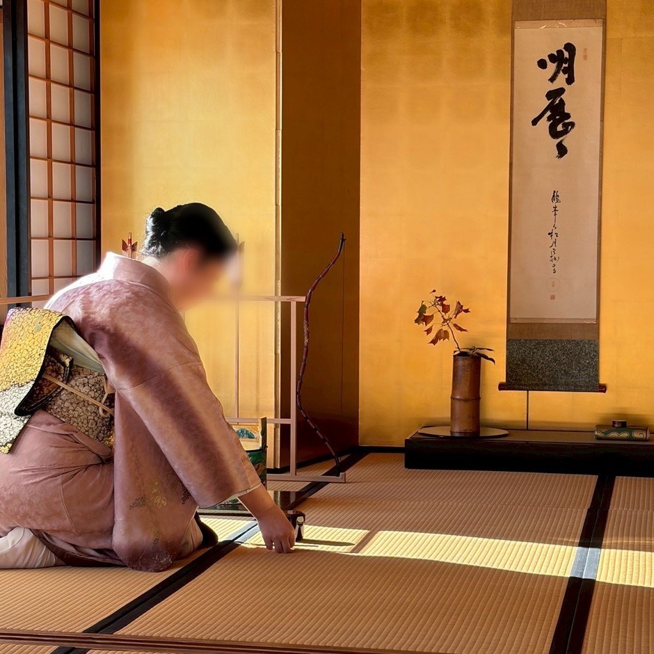 掛物と茶花をしつらえた松の御茶屋でお点前をする和装姿の人。昨年度の茶会の様子